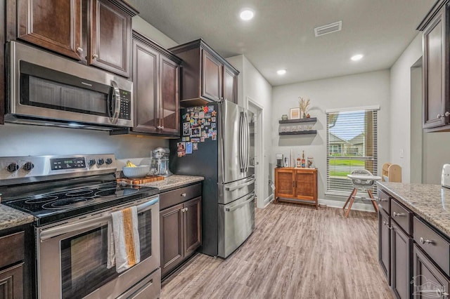 kitchen with appliances with stainless steel finishes, light wood-style flooring, dark brown cabinets, light stone counters, and recessed lighting