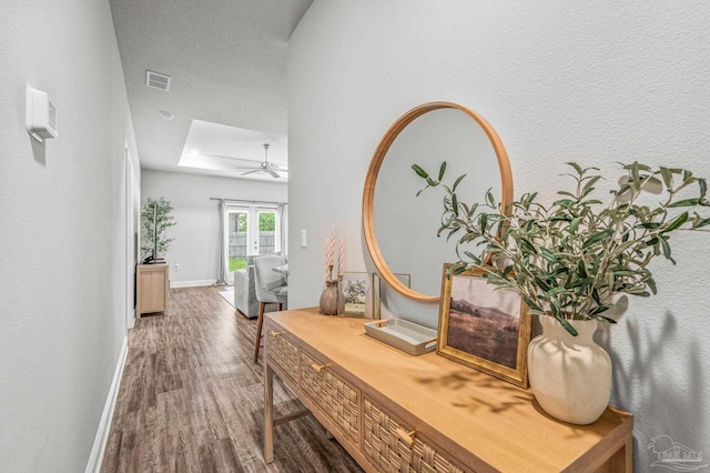 hallway featuring wood finished floors, a skylight, and baseboards
