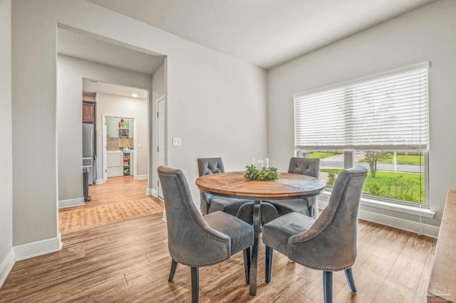 dining room with light wood-style floors, baseboards, and washer / clothes dryer
