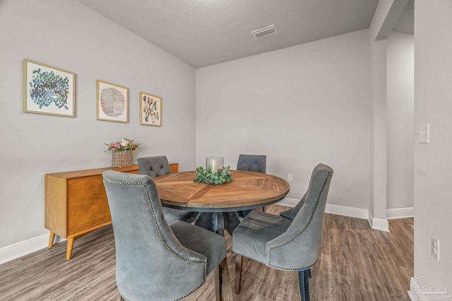 dining room with wood finished floors, baseboards, and lofted ceiling
