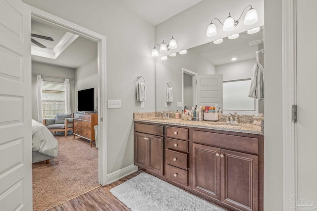 ensuite bathroom featuring wood finished floors, double vanity, ceiling fan, and baseboards