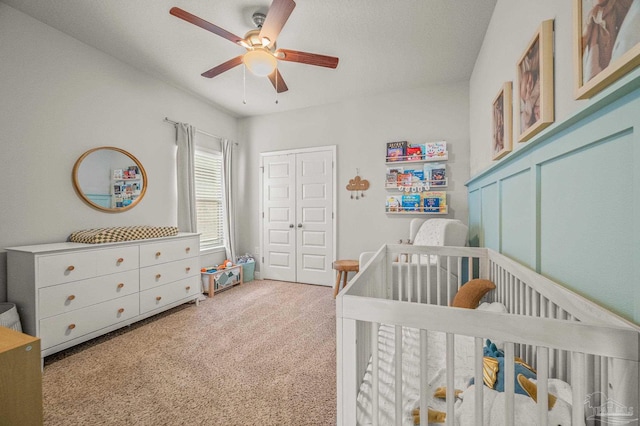 carpeted bedroom with a nursery area and ceiling fan