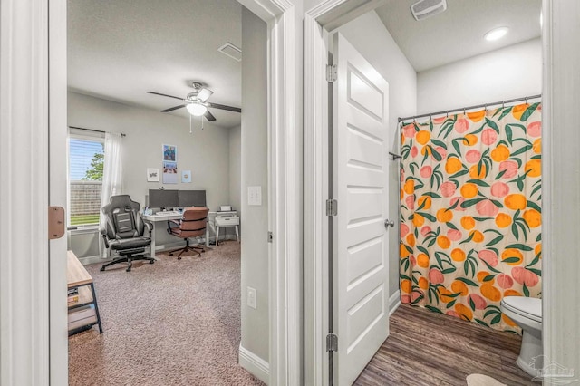 carpeted office space with ceiling fan and baseboards