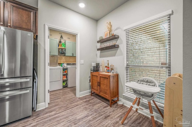 kitchen with freestanding refrigerator, washing machine and clothes dryer, open shelves, light wood-style flooring, and baseboards