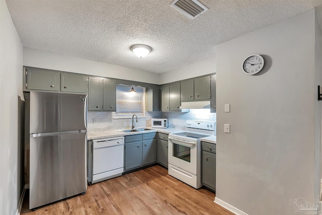 6205 E Forest Pines Dr, Pensacola, FL 32526 - kitchen with white appliances, light countertops, under cabinet range hood, light wood-type flooring, and backsplash