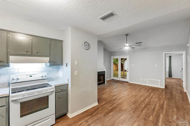 6205 E Forest Pines Dr, Pensacola, FL 32526 - kitchen featuring electric stove, under cabinet range hood, light countertops, a fireplace with flush hearth, and vaulted ceiling