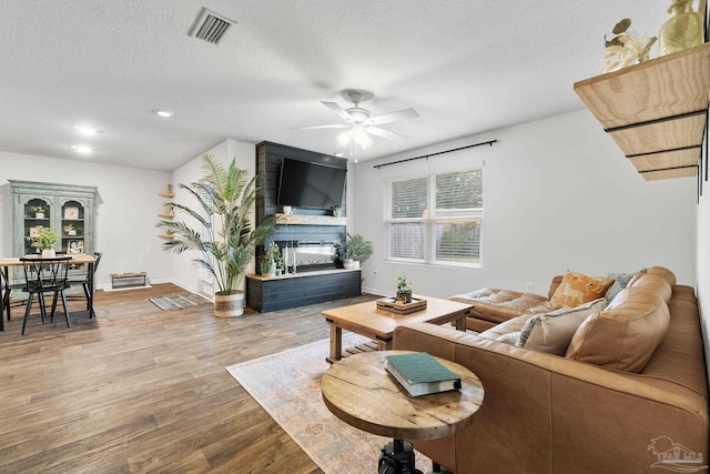 living room with wood-type flooring, a textured ceiling, and ceiling fan