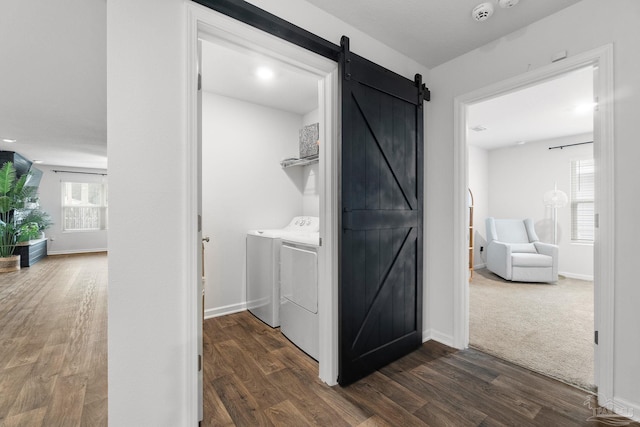 washroom with washer and dryer, a barn door, and dark hardwood / wood-style flooring