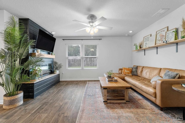 living room with ceiling fan, dark hardwood / wood-style flooring, and a textured ceiling