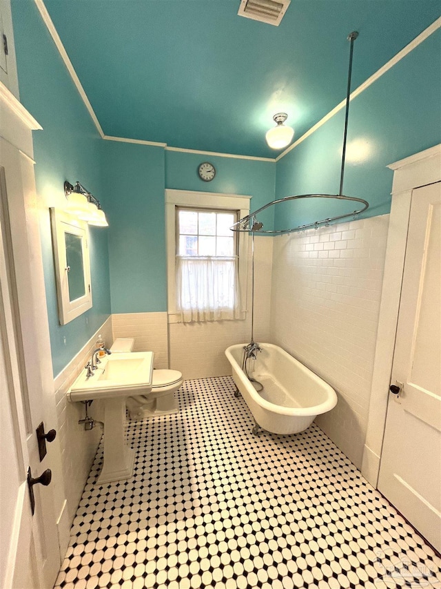 1011 N Reus St, Pensacola, FL 32501 - bathroom with visible vents, a wainscoted wall, ornamental molding, tile walls, and toilet