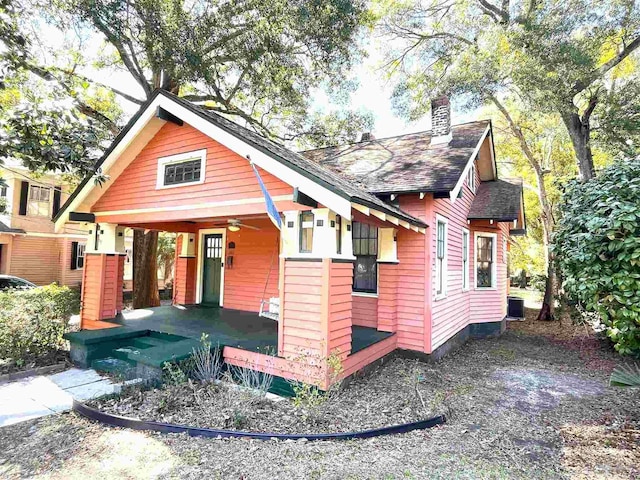 view of front of house featuring a porch, a chimney, and central AC unit