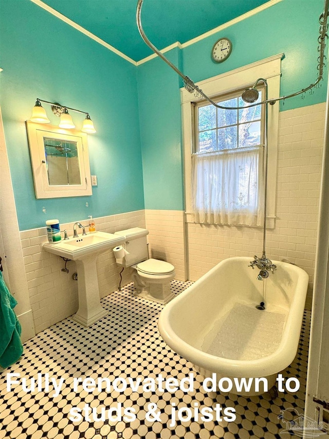 1011 N Reus St, Pensacola, FL 32501 - full bathroom with wainscoting, a freestanding bath, tile walls, and toilet