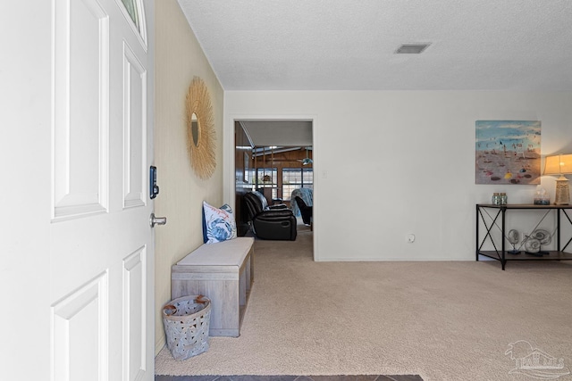 hallway with light carpet and a textured ceiling