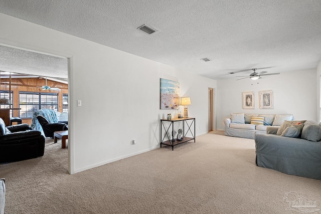 carpeted living room featuring ceiling fan, wooden walls, and a textured ceiling