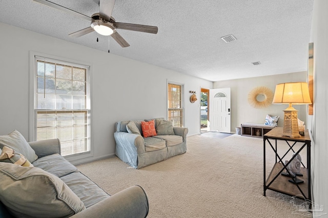 carpeted living room featuring ceiling fan and a textured ceiling