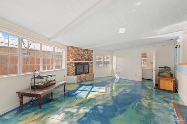 living room with a fireplace, concrete floors, beamed ceiling, and a wealth of natural light