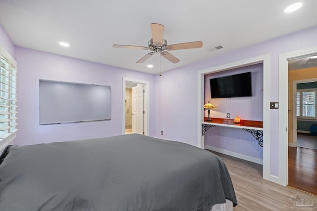 bedroom with ceiling fan, light hardwood / wood-style floors, and multiple windows