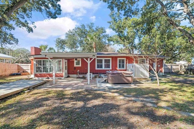 back of house featuring a patio, a yard, and a hot tub