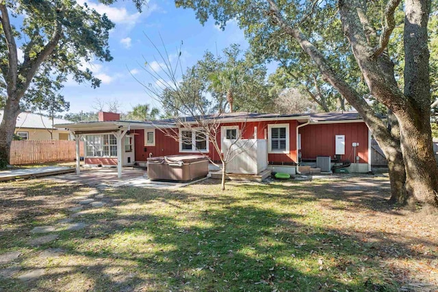 back of house with a lawn, central air condition unit, a patio, and a hot tub