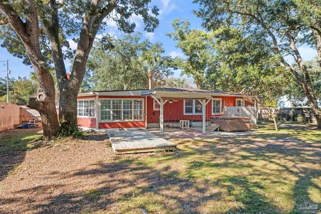 rear view of house with a patio area, a hot tub, and a lawn