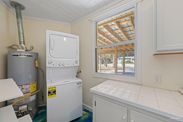 laundry room with ornamental molding, cabinets, stacked washer and clothes dryer, and gas water heater