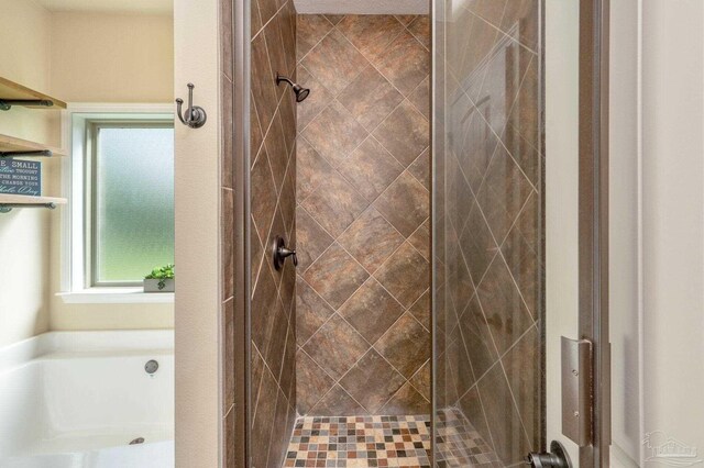 bathroom with a stall shower and a bath