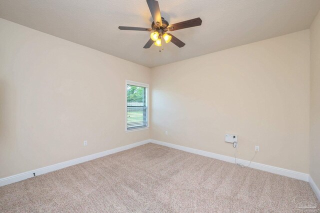 spare room featuring a ceiling fan, baseboards, and light colored carpet