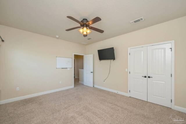 unfurnished bedroom featuring carpet flooring, ceiling fan, baseboards, visible vents, and a closet