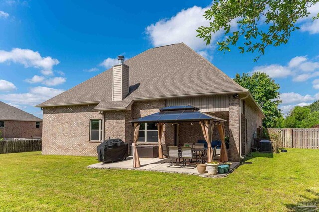 rear view of house with a gazebo, brick siding, a fenced backyard, a patio, and a yard