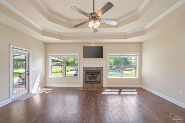unfurnished living room featuring plenty of natural light, ornamental molding, a raised ceiling, and dark wood-type flooring