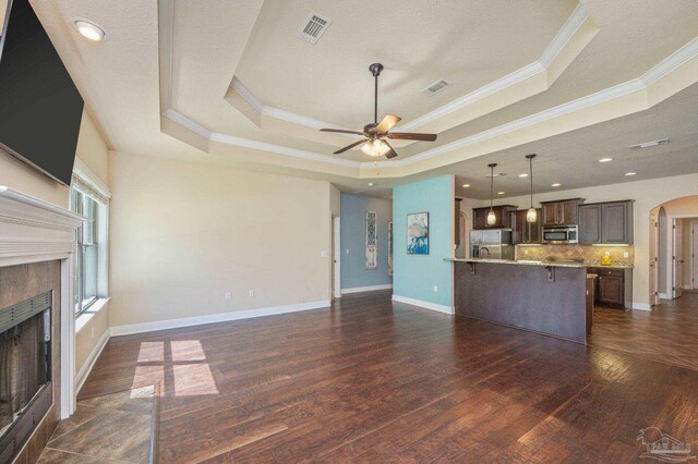 unfurnished living room with crown molding, ceiling fan, a tray ceiling, and a high end fireplace