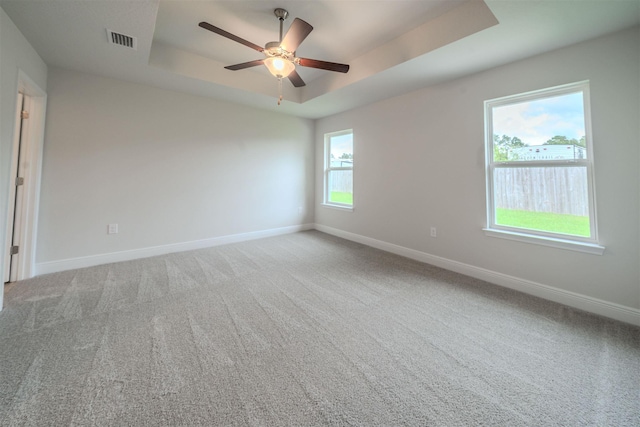 unfurnished room featuring ceiling fan, carpet flooring, and a raised ceiling