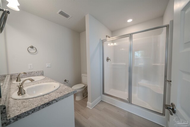 bathroom with vanity, toilet, a shower with door, and hardwood / wood-style floors