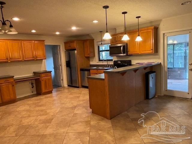 kitchen featuring stainless steel appliances, decorative light fixtures, a kitchen bar, sink, and kitchen peninsula