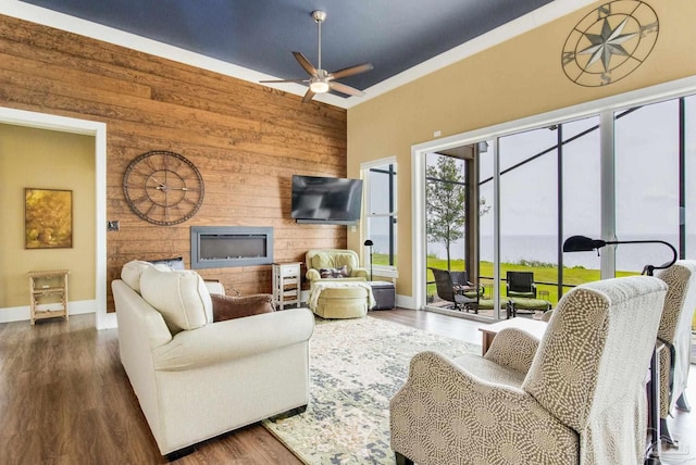 living room featuring a fireplace, wood finished floors, a ceiling fan, and wooden walls