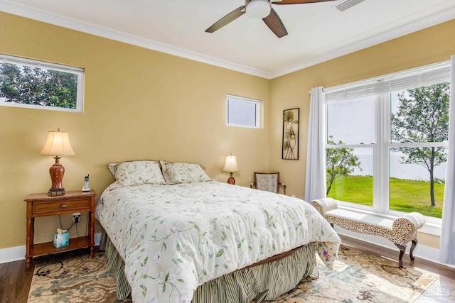 bedroom with multiple windows, crown molding, baseboards, and wood finished floors