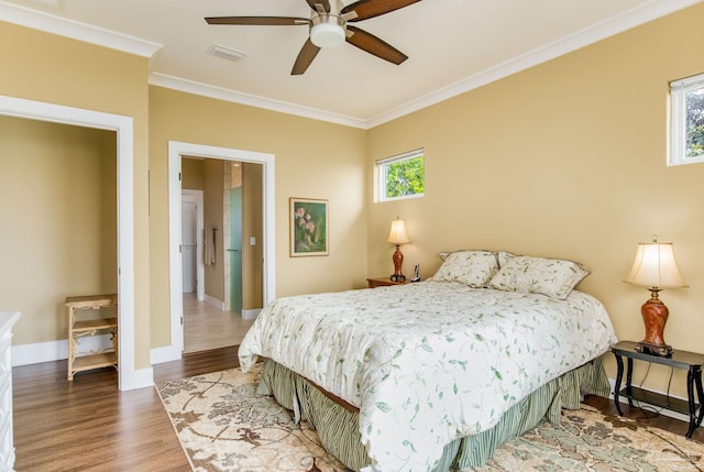 bedroom featuring baseboards, visible vents, crown molding, and wood finished floors