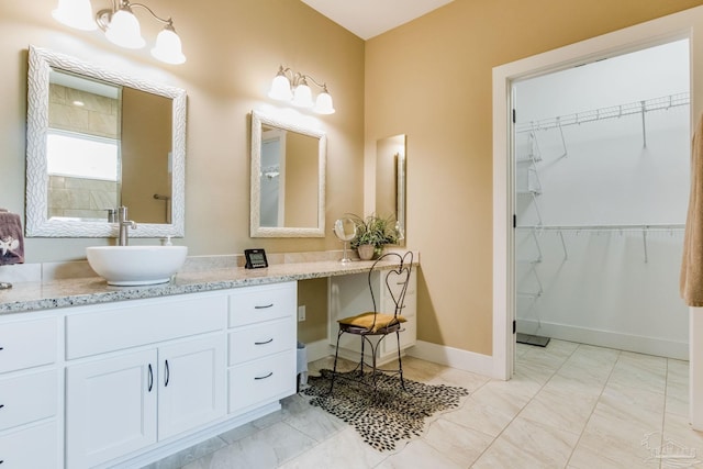 bathroom featuring baseboards, a spacious closet, and vanity