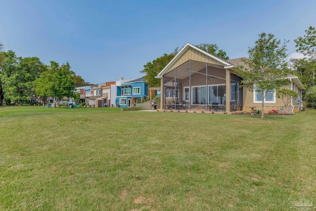 rear view of house featuring a yard and a sunroom