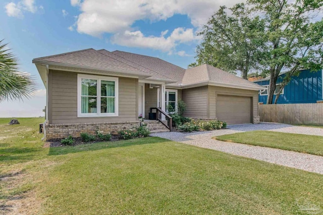 view of front of property featuring brick siding, roof with shingles, an attached garage, a front yard, and driveway