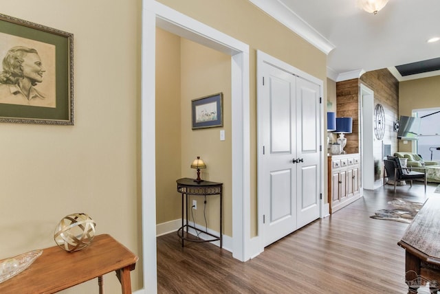 corridor with ornamental molding, wood finished floors, and baseboards