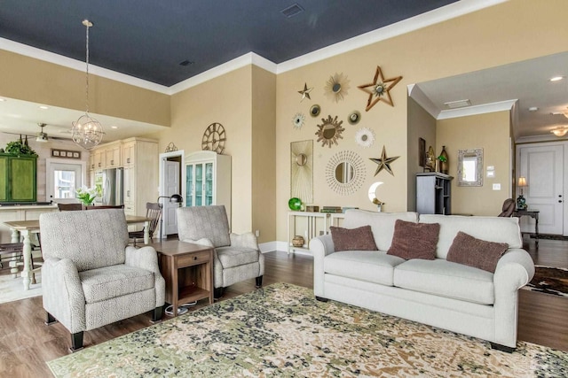 living area with baseboards, visible vents, a towering ceiling, wood finished floors, and crown molding