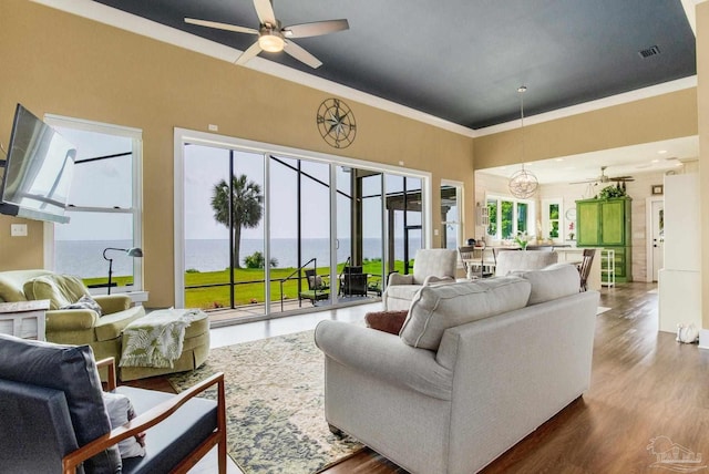 living area with ceiling fan, ornamental molding, wood finished floors, and visible vents