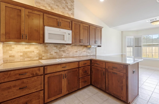 kitchen featuring kitchen peninsula, backsplash, white appliances, vaulted ceiling, and light tile patterned floors