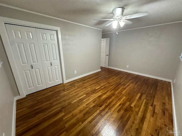 unfurnished bedroom featuring a textured ceiling, ceiling fan, dark wood-type flooring, and crown molding