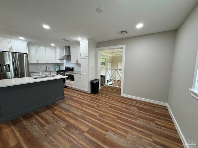 kitchen featuring dark wood-type flooring, sink, white cabinets, wall chimney range hood, and appliances with stainless steel finishes