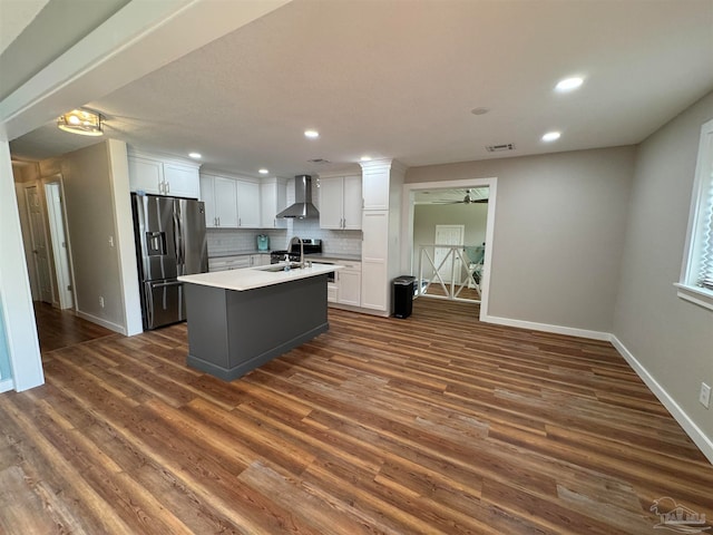 kitchen featuring a center island with sink, wall chimney range hood, white cabinetry, stainless steel refrigerator with ice dispenser, and dark hardwood / wood-style floors