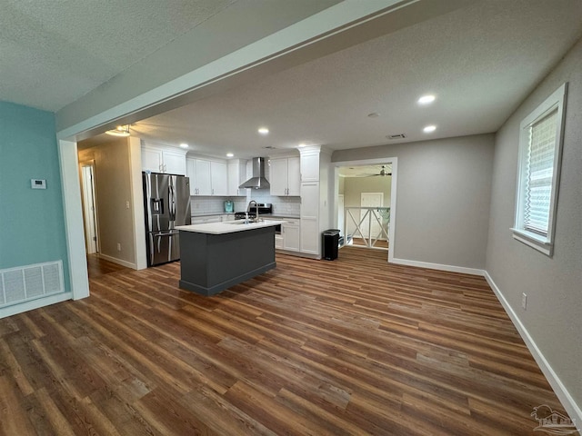 kitchen featuring dark hardwood / wood-style floors, a kitchen island with sink, white cabinets, stainless steel refrigerator with ice dispenser, and wall chimney exhaust hood