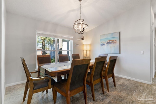 dining area featuring wood-type flooring, vaulted ceiling, and a notable chandelier