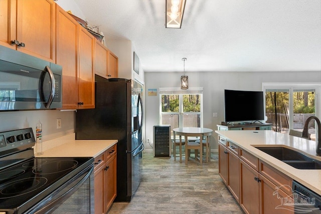 kitchen with hardwood / wood-style floors, pendant lighting, sink, black appliances, and a textured ceiling